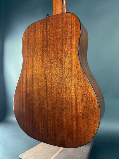 Back view of a wooden acoustic guitar on a gray background