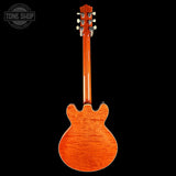 Back view of a wooden electric guitar with a visible brand logo in the corner.
