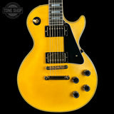 Yellow electric guitar with a black pickguard on a black background, featuring 'Tone Shop' logo.