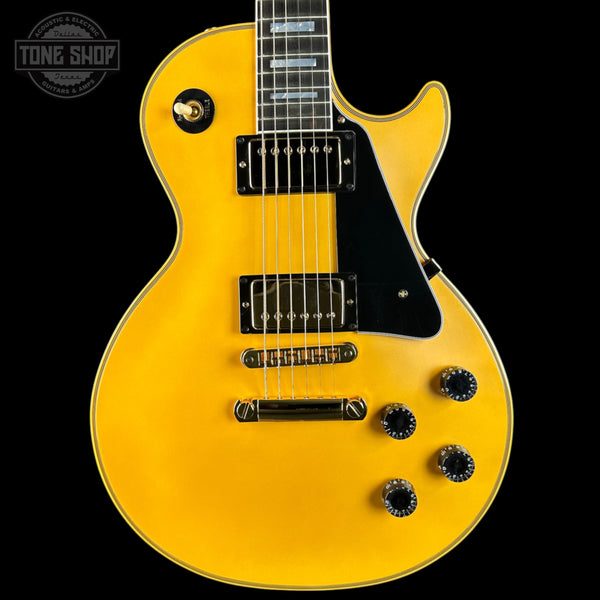 Yellow electric guitar with a black pickguard on a black background, featuring 'Tone Shop' logo.