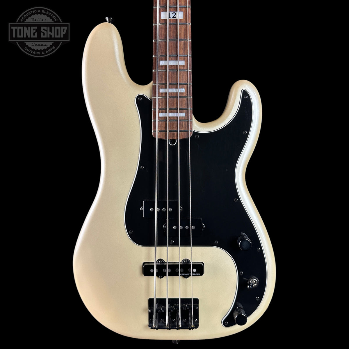 A classic four-string bass guitar with a cream-colored body, a black pickguard, and a dark brown maple fretboard, shown against a solid black background.