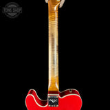 Close-up of a red electric guitar with a visible brand logo on a black background