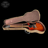 A double-cutaway electric guitar with a sunburst finish, displayed inside an open vintage-style hard case on a solid black background. A Tone Shop logo is visible in the top-left corner.