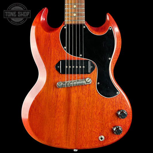A classic electric guitar with a reddish-orange sunburst finish, black pickguard, and chrome hardware, shown against a solid black background with a Tone Shop watermark in the top-left corner.