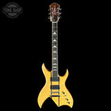 A gold-finish electric guitar with a dark brown headstock and black hardware, shown vertically against a solid black background. A Tone Shop watermark is visible in the top-left corner.