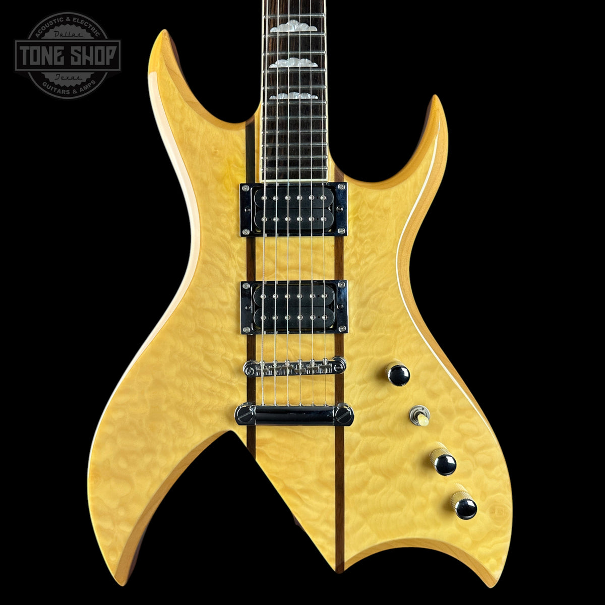 A close-up of an electric guitar body in a natural maple flamed finish, featuring black hardware, control knobs, and a dark fretboard, shown against a solid black background with a Tone Shop watermark in the top left corner.