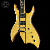 A double-cutaway electric guitar with a natural flamed maple top, shown against a solid black background. The guitar features black hardware, black pickups, and a dark fretboard.