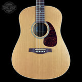 Acoustic guitar with a visible brand logo on a black background