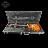 Glossy electric guitar in a hard-shell case with 'Tone Shop' branding.