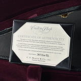 A framed Certificate of Authenticity plaque inside a black guitar case, displayed on a burgundy velvet surface. The certificate reads Custom Shop and C.