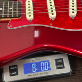 Red electric guitar on a digital scale displaying weight