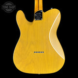 Back of a yellow electric guitar with brand label on a black background