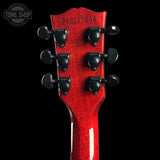 Close-up of a red guitar headstock with tuning pegs on a black background, featuring 'Tone Shop' logo.