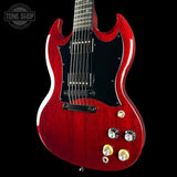Red electric guitar with a black pickguard on a black background, featuring the Tone Shop logo.