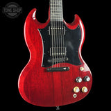 Red electric guitar with a black pickguard on a black background, featuring the Tone Shop logo.