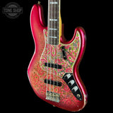 A Fender Jazz electric bass guitar with a vibrant red and gold paisley patterned finish, shown against a solid black background. The brand logo 'Tone Shop' is visible as an overlay in the top-left corner.