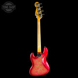 A red electric guitar shown from the back against a solid black background, featuring a glossy red body with gold paisley patterns, a natural wood neck, and a yellow headstock.