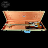 A sunburst Fender bass guitar inside an open cream-colored hard case with a peach-pink velvet interior, shown against a solid black background.