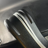 Close-up of a car door handle with a white strip on a black car interior.