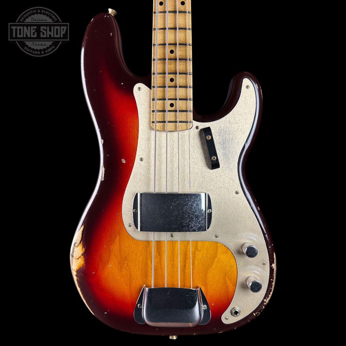 A vintage-style electric bass guitar with a sunburst finish, featuring a dark red outer edge fading to a bright yellow-orange center, a cream pickguard, and a maple neck, shown against a solid black background.