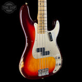 A vintage-style electric bass guitar with a sunburst finish, featuring a red, amber, and black gradient body, a cream pickguard, and a maple neck, shown against a solid black background.