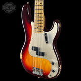 A classic Fender Jazz Bass electric guitar with a vintage sunburst finish, featuring a dark red outer edge, a bright orange middle band, and a cream-colored pickguard. The neck is made of maple wood with black dot inlays, and the headstock is not visible.