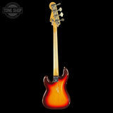 A classic electric bass guitar with a sunburst finish, shown from the back against a solid black background. The headstock features a vintage-style design with four white tuning pegs.