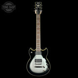 Silver electric guitar on a black background with 'Tone Shop' logo.