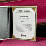 A Gibson Custom Certificate of Authenticity insert for a Murphy Lab Ultra Heavy Aging instrument, displayed inside an open gold-toned presentation box with a dark gray interior and pink velvet background.