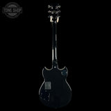 Back view of a black electric guitar on a white background with 'Tone Shop' logo.