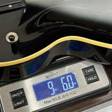 Digital kitchen scale displaying weight with a black and gold kitchen appliance on top.