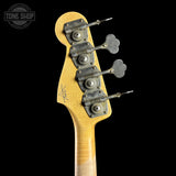 Close-up of the back of a bass guitar headstock with four metal tuning pegs and a light natural wood finish, shown against a black background with a Tone Shop watermark in the upper left.