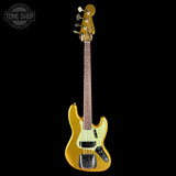 A gold metallic electric bass guitar with a cream pickguard and dark fretboard, shown vertically against a solid black background. A Tone Shop watermark is visible in the top-left corner.