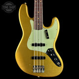 A gold-finished electric bass guitar with a pale mint green pickguard, black hardware, and a dark wood fretboard, shown against a solid black background with a Tone Shop watermark in the top left.