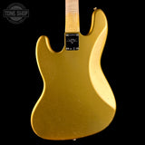 The back view of a gold-finished electric guitar body, featuring a black plate with a 'Tone Shop' logo and a light-colored neck joint, set against a solid black background.