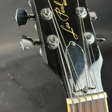 Gibson guitar headstock with tuning pegs on a blurred background