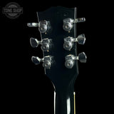 Guitar headstock with tuning pegs on a black background