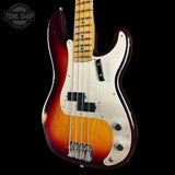 A classic four-string bass guitar with a sunburst finish, featuring a dark red outer edge fading to amber and orange, a cream pickguard, and a maple neck, shown against a solid black background.