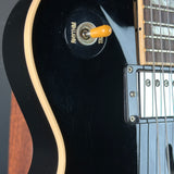 Close-up of a black electric guitar with a pickup selector switch.