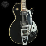 Black electric guitar with chrome details on a black background, featuring the 'Tone Shop' logo.