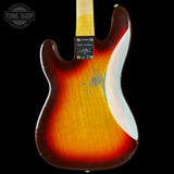 The back of a vintage Fender Stratocaster electric guitar with a sunburst finish, showing a yellow-orange center fading to dark brown and black edges, photographed against a solid black background.