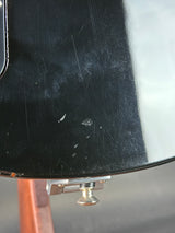 Close-up of a black guitar body with visible wear and tear.