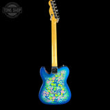 A custom-painted blue electric guitar shown from the back against a solid black background, featuring a vibrant multicolor floral pattern on the body and a natural maple neck.