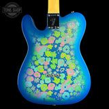 A Fender Telecaster-style electric guitar body shown from the back, featuring a vibrant blue base with a dense, multicolored retro floral pattern in pink, green, and yellow. The neck joint is visible at the top, and a Tone Shop watermark is in the upper left corner.