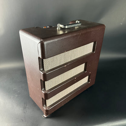 Brown speaker cabinet with metallic grille on a gray background