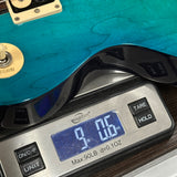 Guitar on a digital scale displaying weight, with a blue background