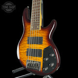 Electric bass guitar with a sunburst finish on a stand, brand 'Tone Shop' visible.