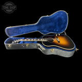 Acoustic guitar in a blue-lined hard case with 'Tone Shop' logo.