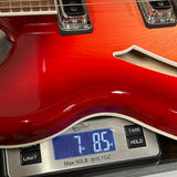 Close-up of a glossy red electric guitar body resting on a digital scale displaying 7.85 lbs.