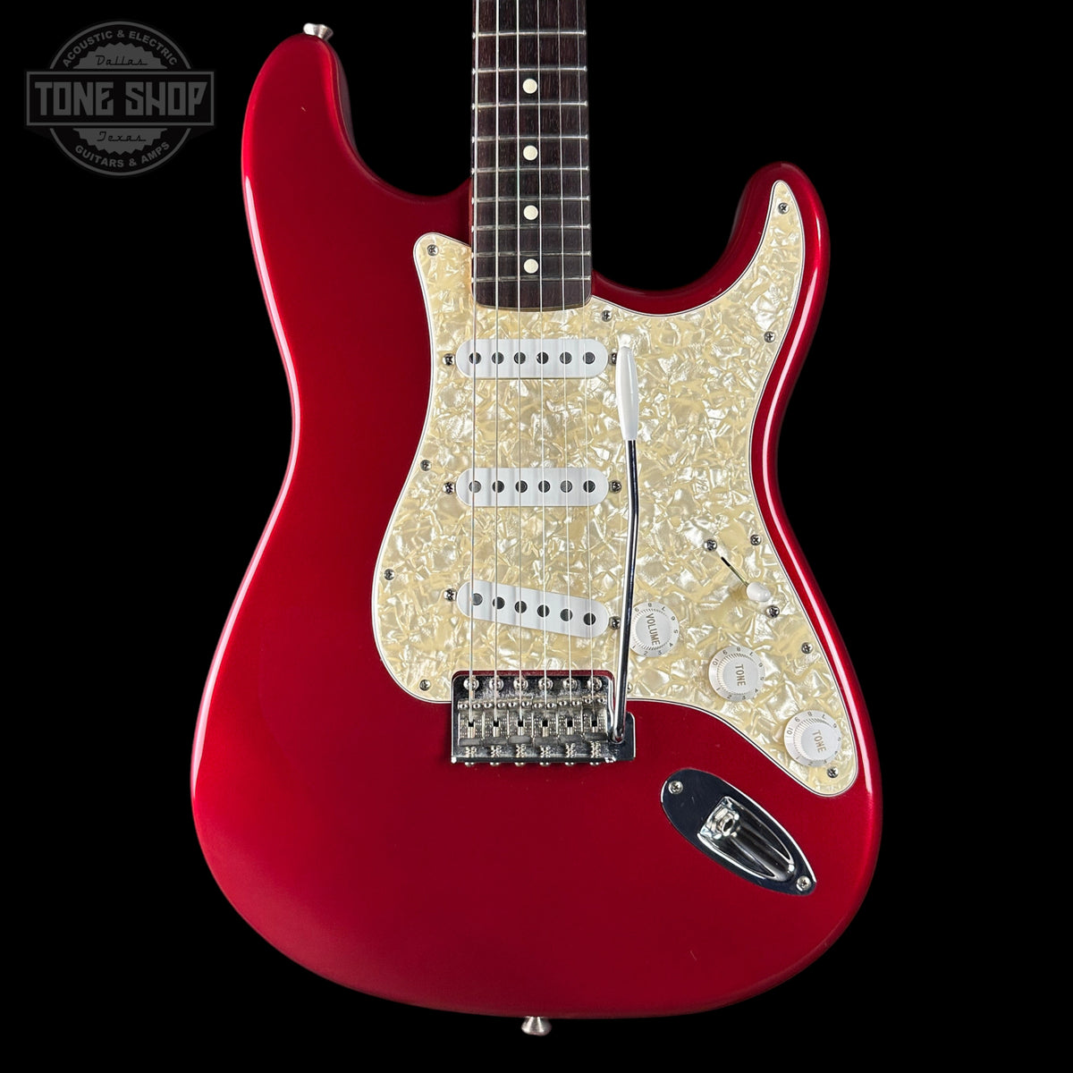 Red electric guitar with a white pickguard on a black background, featuring 'Tone Shop' branding.
